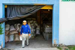 a man walking out of a room with several bags of seed behind him