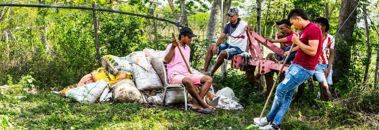 a group of people sitting together surrounded with farming supplies