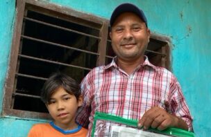 an adult man and child smiling, holding a certificate.