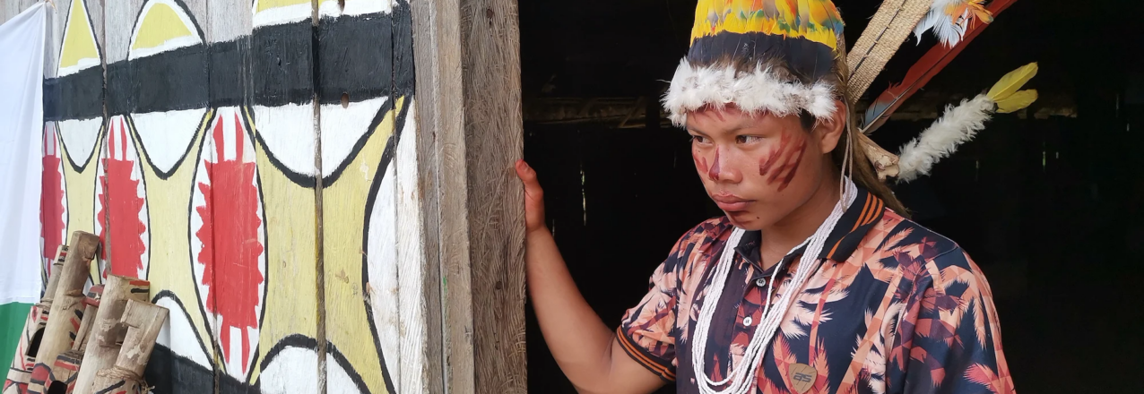 an indigenous man adorned with traditional jewelry, face paint, and head dress